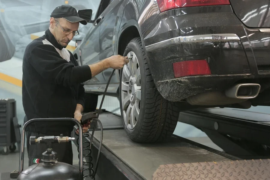 Un meccanico che pompa la ruota di un'auto con un'unità console