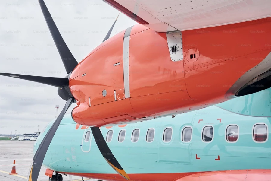 Avión turbohélice de color naranja y azul estacionado en la pista