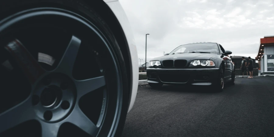 A black car with white rims on the road