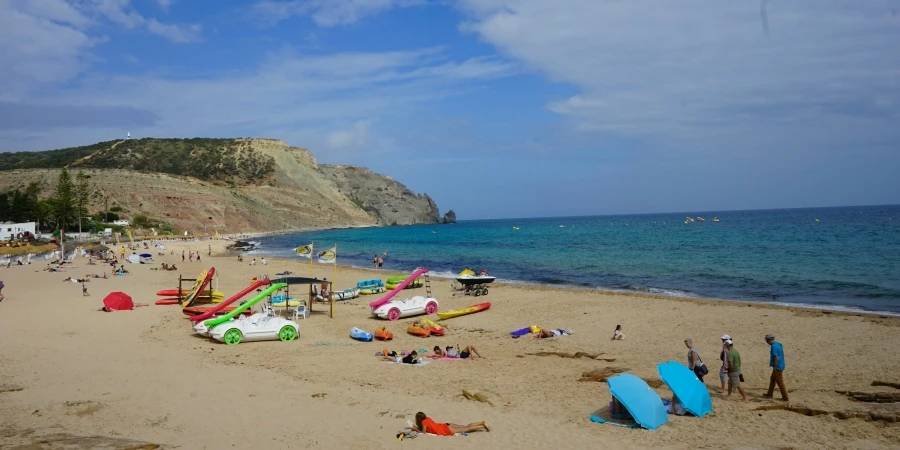 Grupa ludzi stoi na szczycie piaszczystej plaży