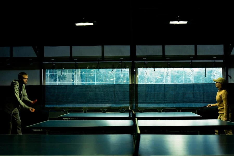 A man and a woman playing ping pong in a dark room