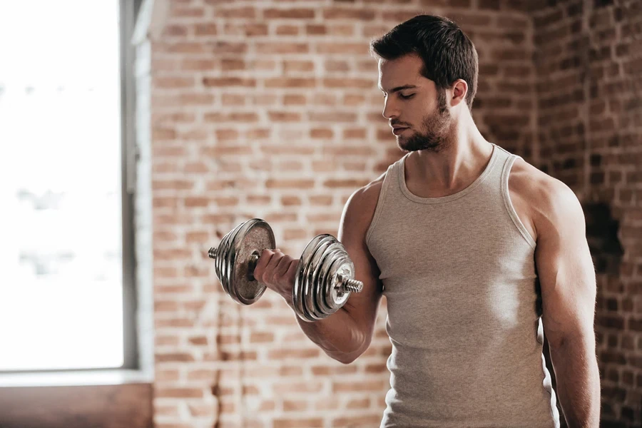 Un hombre que viste camisetas deportivas sin mangas y entrena en el gimnasio.