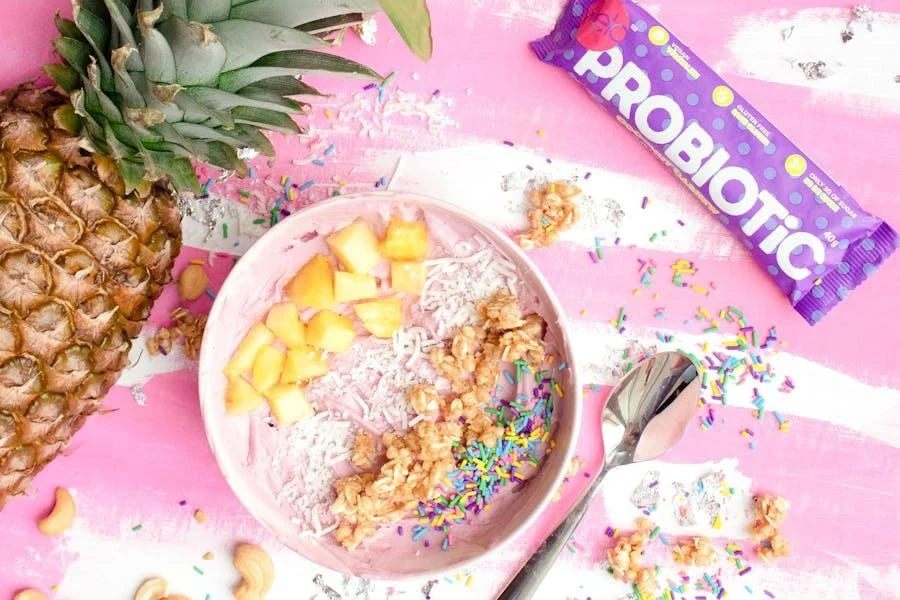 A pineapple next to a bowl and a probiotic bar