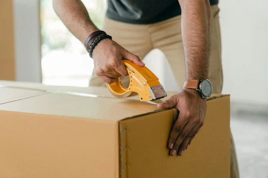 Um pequeno empresário embalando produtos em uma caixa de papelão