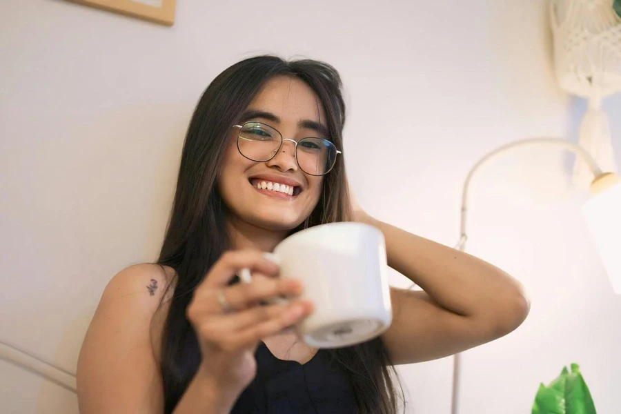 Une femme avec des lunettes tenant une tasse de café