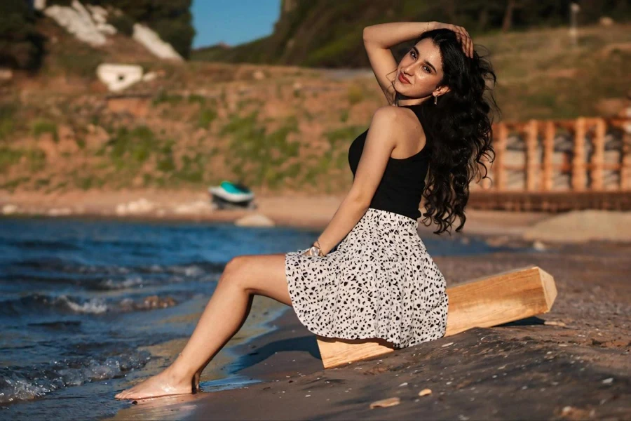 Eine Frau sitzt auf einem Baumstamm am Strand