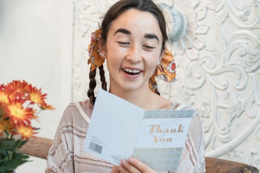 A woman smiling while reading a thank-you note