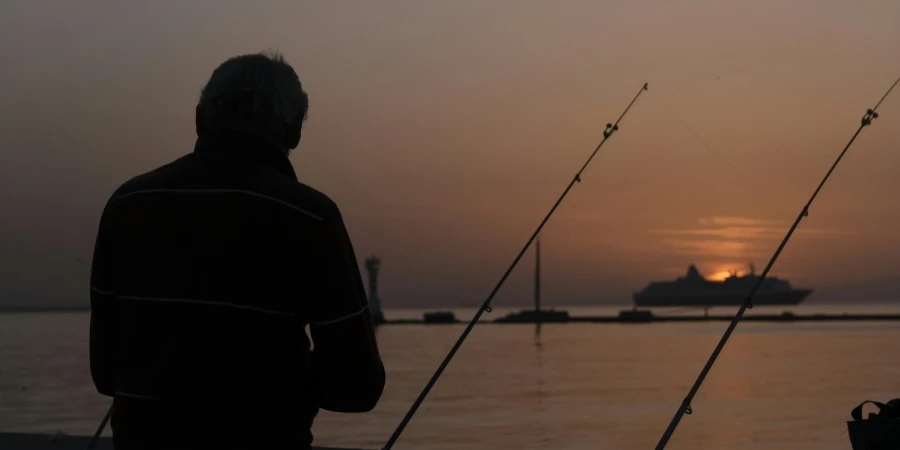 Angler angeln im Meer vom Kai bei Sonnenuntergang