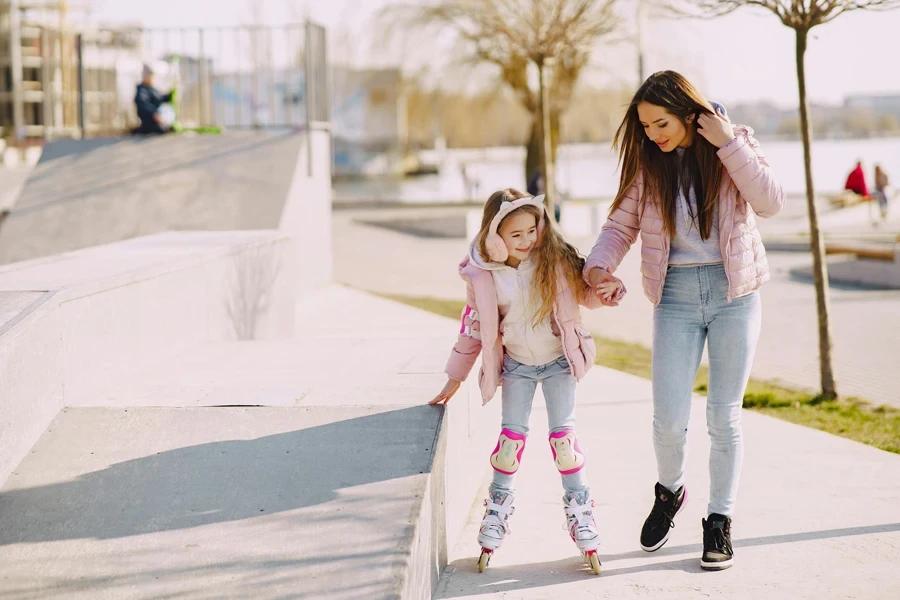 Cheerful girl skating on rollers with young mother