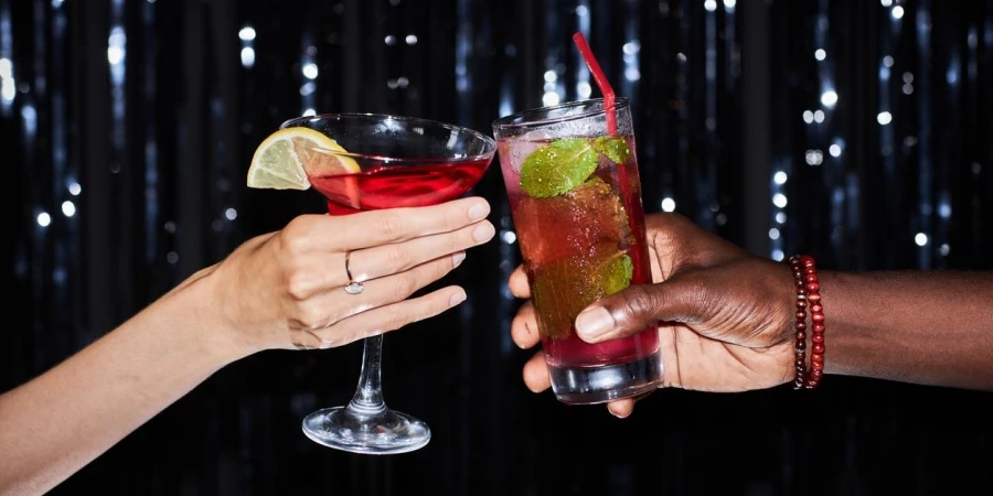 Close-up of two people holding cocktail against glittering party background