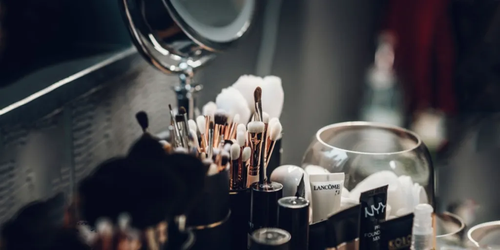 Makeup brushes kept with some other cosmetics near a mirror