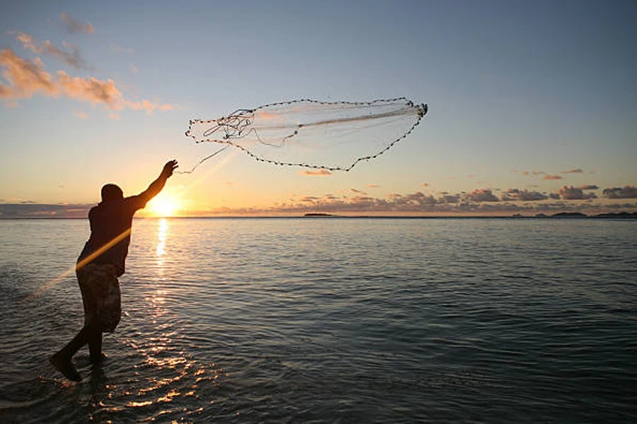 Homem atirando rede preta para o ar ao nascer do sol