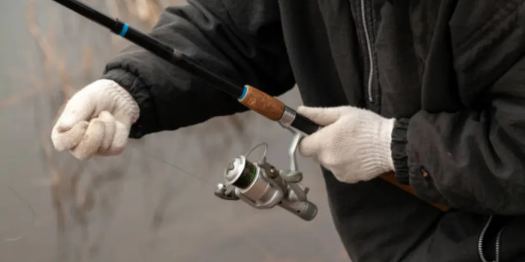 Homem usando luvas de pesca enquanto segura uma vara de pescar