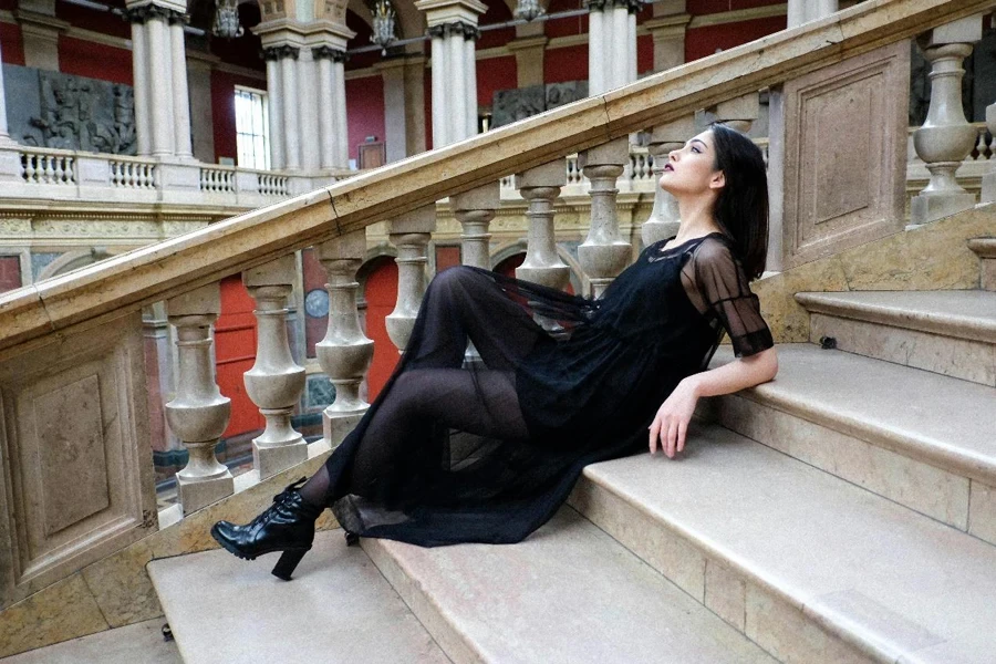 Mujer elegante tumbada en las escaleras de mármol del museo