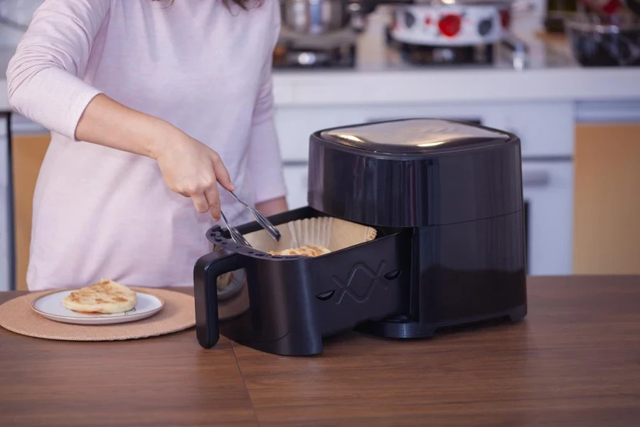 Wanita Memasak Makanan di Air Fryer di Dapur