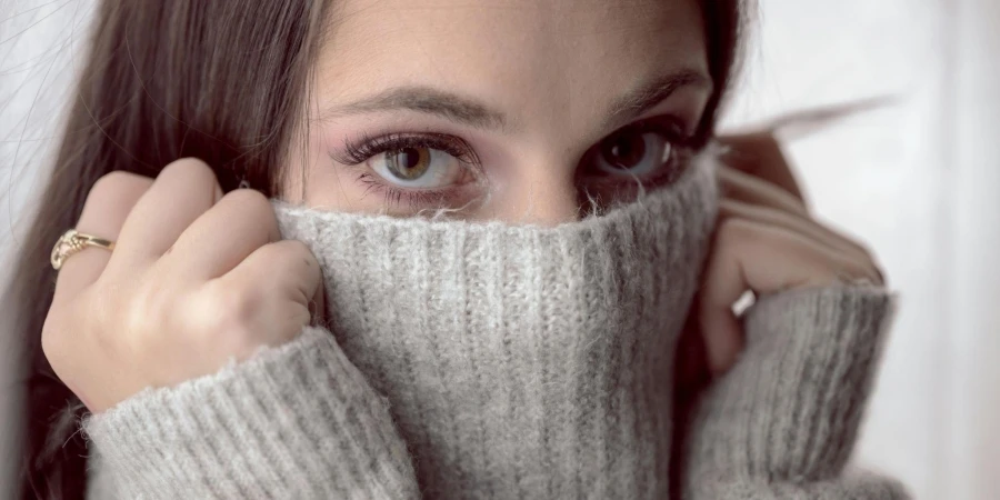 Donna che si copre il viso con un tessuto di maglia grigio