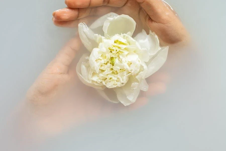 Woman gently holding a white flower in water