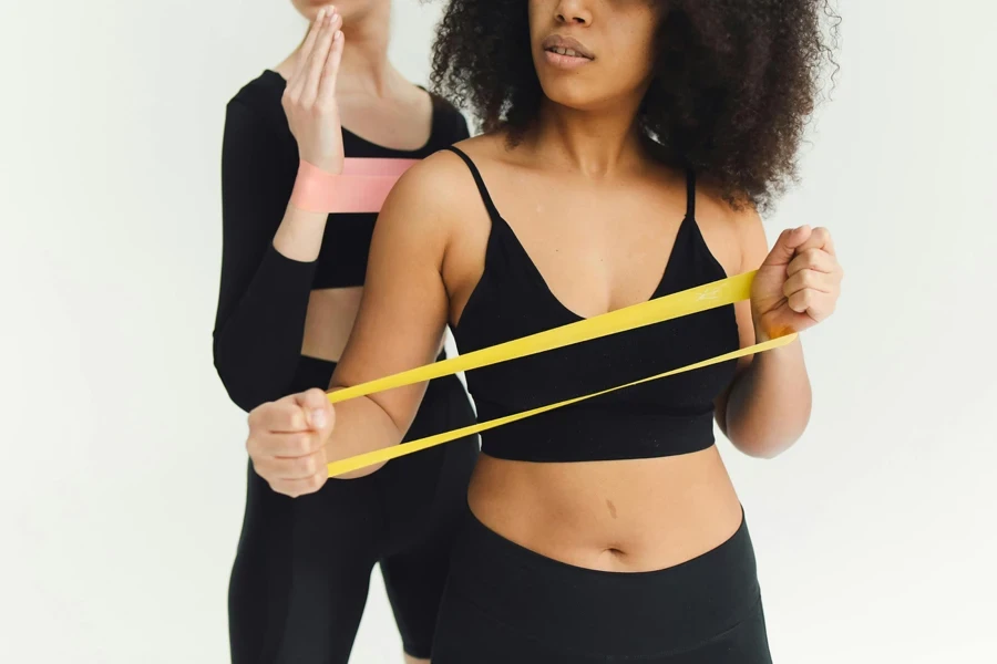 Femme En Soutien-gorge De Sport Noir Tenant Une Bande De Résistance Jaune