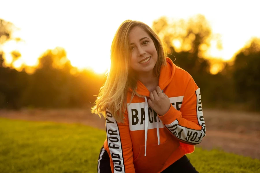 Mujer con sudadera naranja y blanca sonriendo