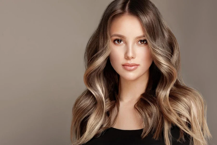 Hermosa modelo joven de cabello castaño con cabello largo, ondulado, denso y teñido.