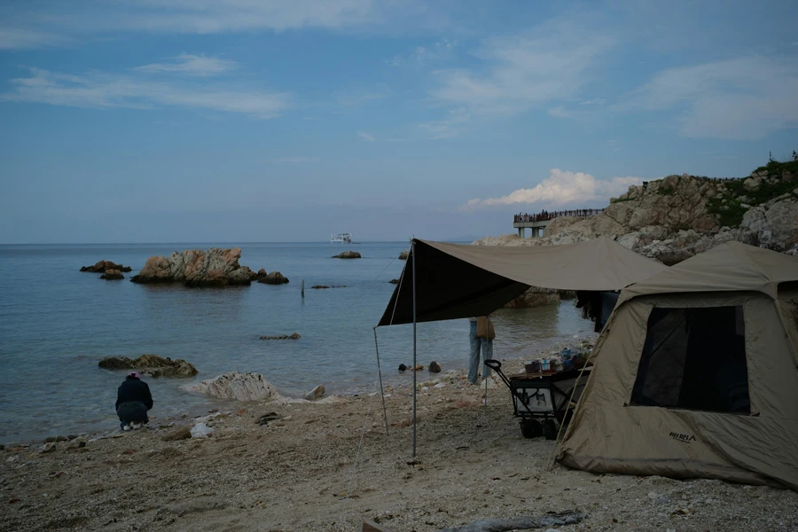 beberapa tenda berdiri di atas pantai berpasir