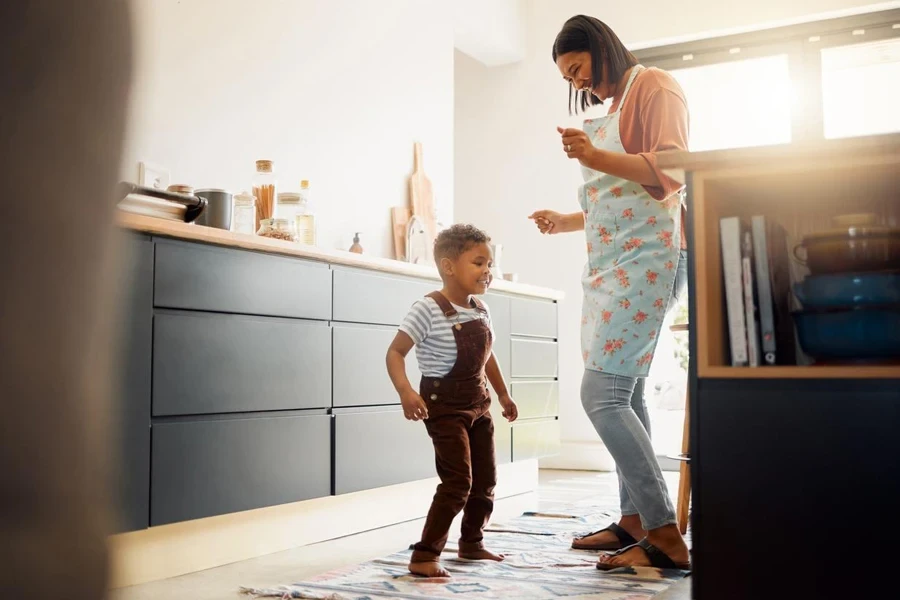 a little mixed race boy dancing and having fun with his mother in a kitchen happy