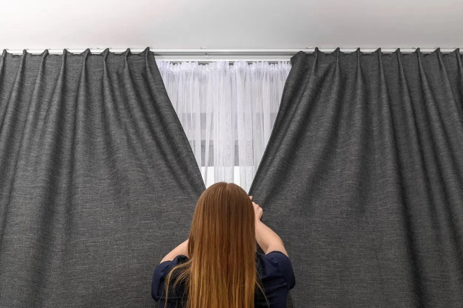 a woman closing blackout curtains for privacy