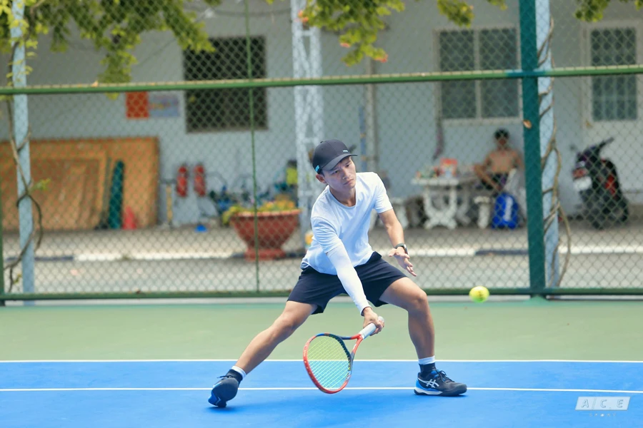 un giovane che tiene in mano una racchetta da tennis su un campo da tennis