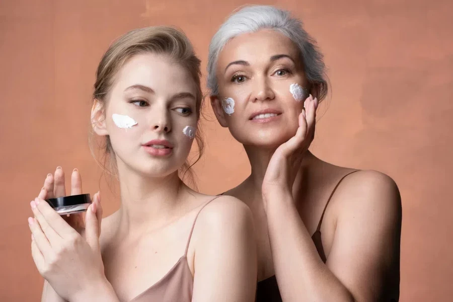 Daughter and mother applying moisturizer to their faces