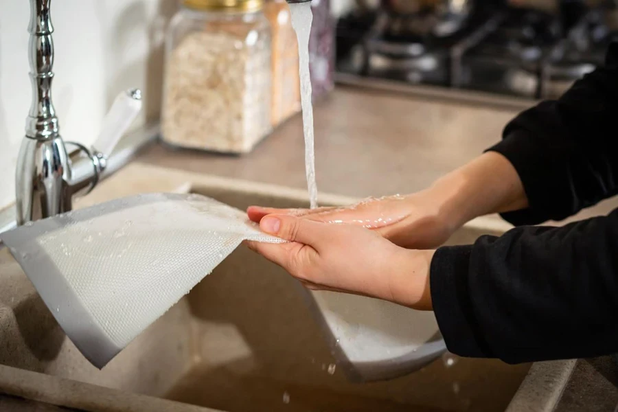 female hands cleaning a silicone baking mat in cold water