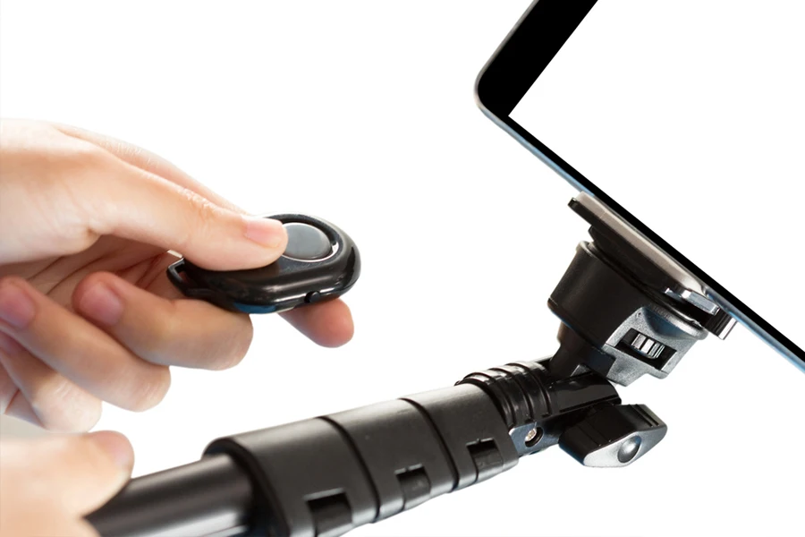 Photo close up of two hands holding a monopod with a remote for Selfie