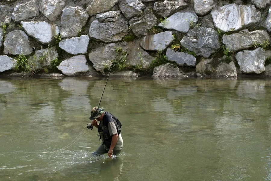 Мужчина ловит рыбу в мутной воде с помощью зонтичных снастей