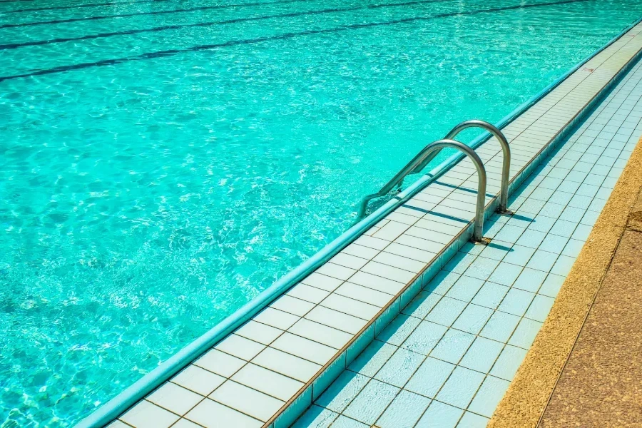 Escada de piscina de metal apoiada sobre os ladrilhos da piscina