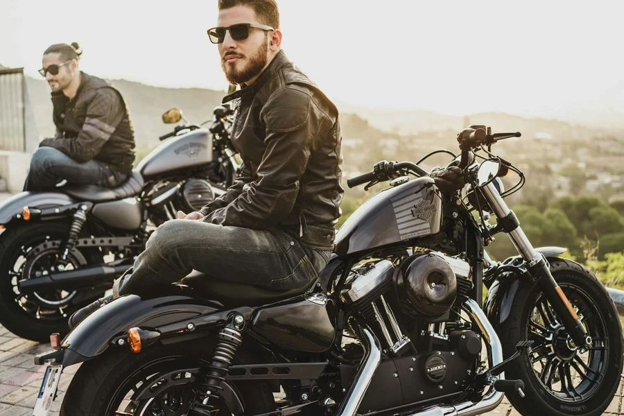 two men sitting on two parked cruiser motorcycles