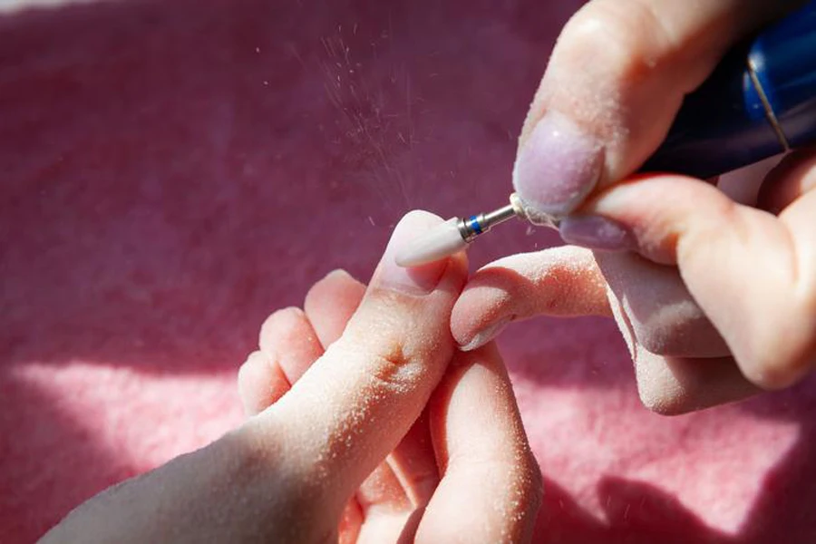 woman hands making self manicure removing pink gel nail polish