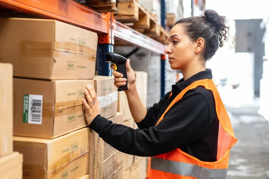 Une femme scanne des cartons avec un lecteur de codes-barres