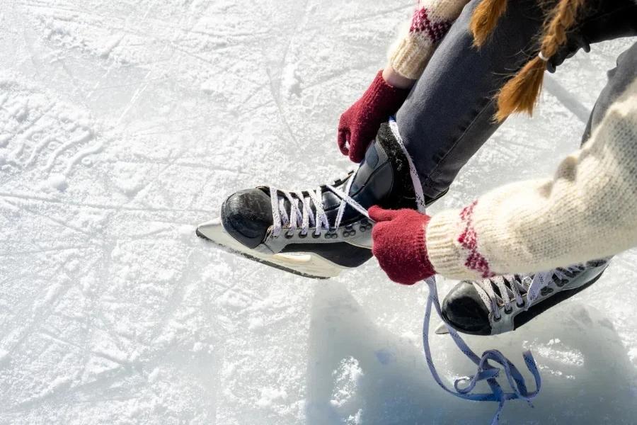 Mujer atando cordones de patines de hockey para una sesión de patinaje