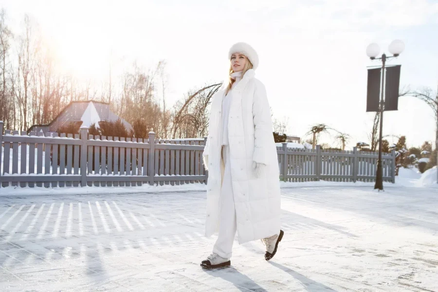 Woman walking outside in a white quilted trench coat