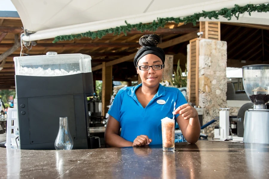 Une barmaid debout à côté d'une machine à glaçons