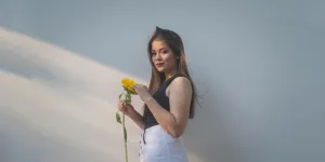 Frau in Jeans mit hoher Taille hält eine Sonnenblume