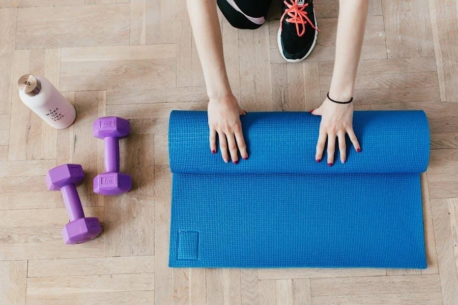 Woman preparing yoga equipment on a wooden floor