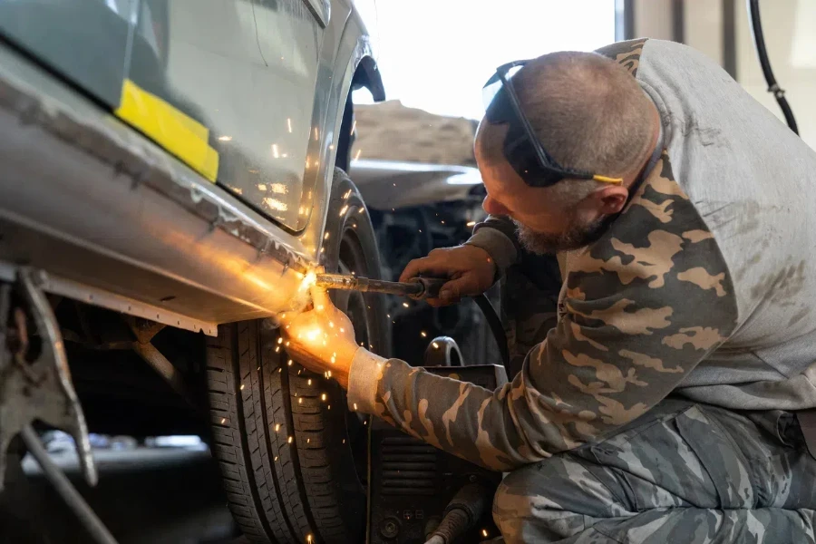 A mechanic wielding a threshold to a car