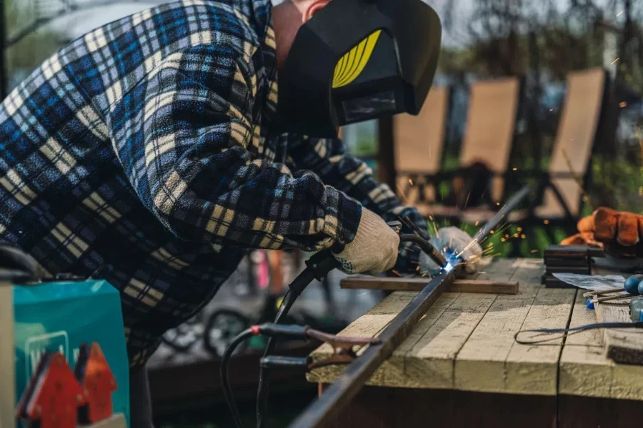 Man welding metal frame in his backyard