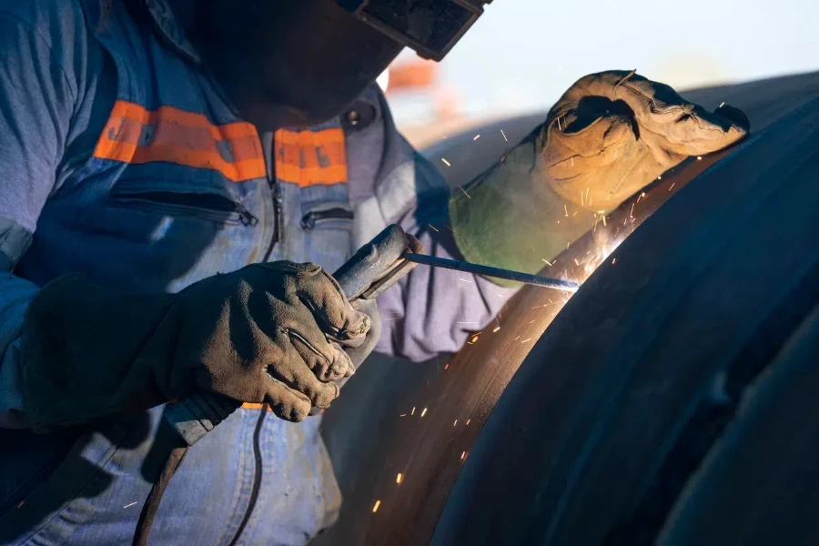 Profesional que utiliza un soldador de varilla sobre un arco metálico