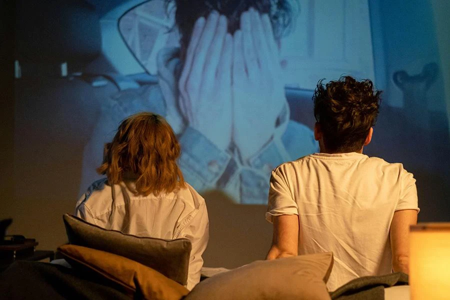 A Romantic Couple Sitting on the Bed while Watching movies