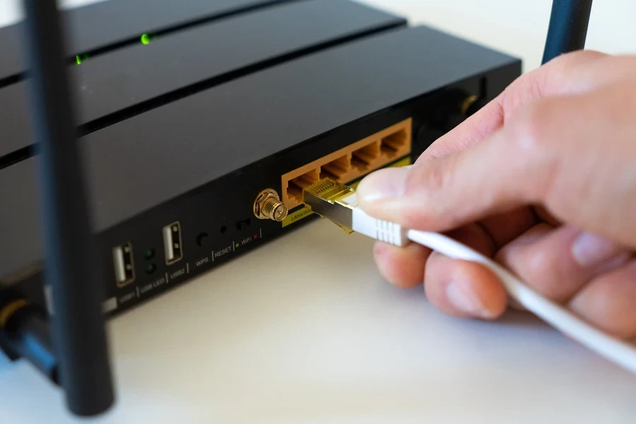 A hand holding a cable to a modem