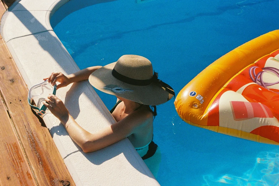 A man sitting on the side of a swimming pool next to an inflatable