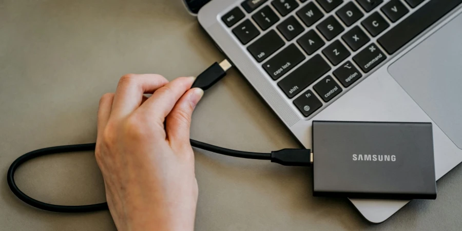 Een persoon sluit een oplader aan op een laptop