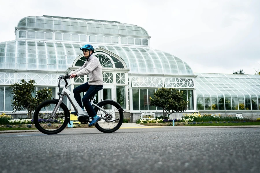 Uma pessoa andando de bicicleta elétrica em frente a uma estufa