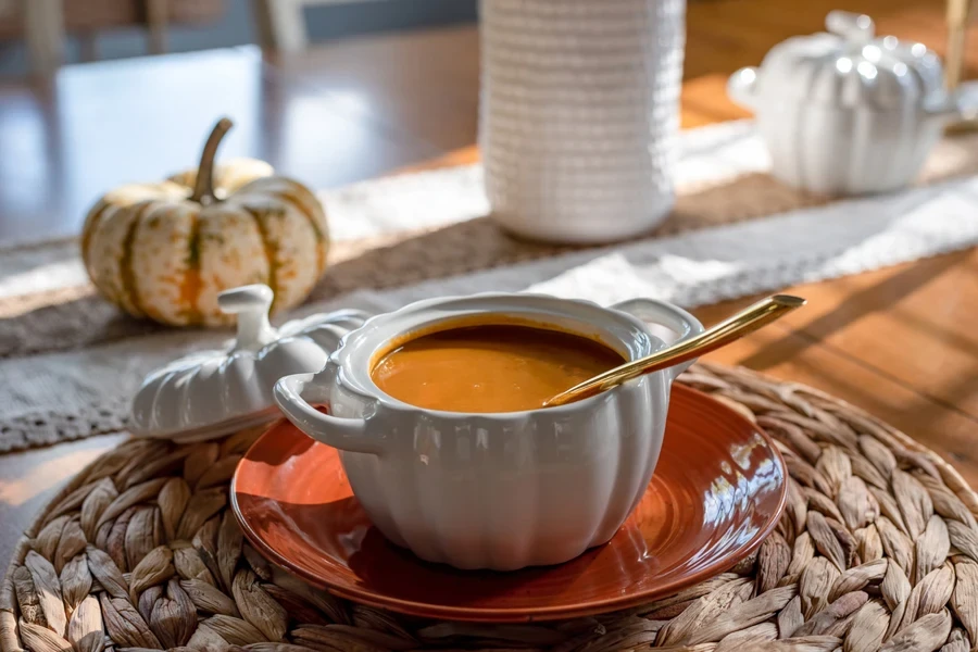 Uma sopa de abóbora em uma pequena terrina com alças